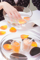 Female hand soaking in glass bowl water. Manicure.