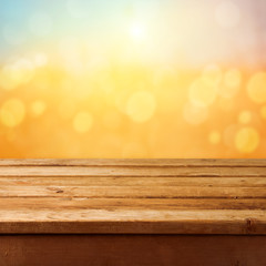 Empty wooden deck table over sunset bokeh background