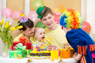 Fototapeta na wymiar baby girl celebrating first birthday with parents and clown