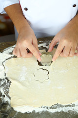 Cook hands making cookies on wooden table