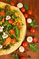 Tasty vegetarian pizza and vegetables on wooden table