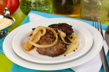 Fried chicken livers on plate on wooden table close-up