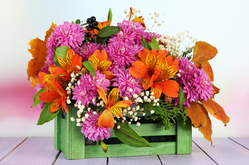 Flowers composition in crate on table on bright background