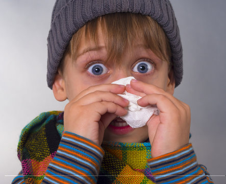 Beautiful boy wipes nose with napkin