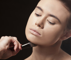 Obraz premium Beautiful woman applying makeup with a brush