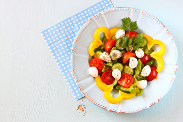 salad with mozzarella and fresh vegetables on wooden table backg