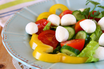 salad with mozzarella and fresh vegetables on wooden table