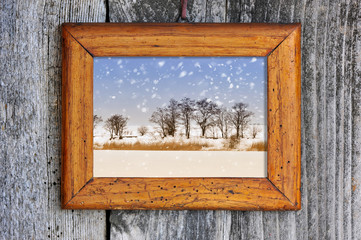Frame with winter landscape on a wooden background