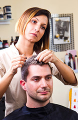 Fototapeta premium Happy female hairstylist setting client's hair