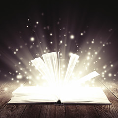 open book with light insideout on wooden background