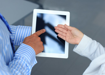 Closeup two modern business people working with digital tablet