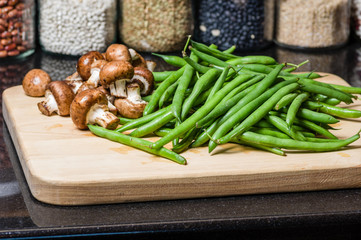 Mushrooms and green beans on a wooden board