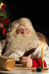 Santa Claus sitting at home and writing a letter