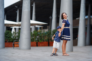 Young mother and her son walking outdoors in city