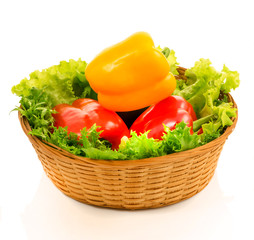colorful sweet peppers are in a basket with lettuce