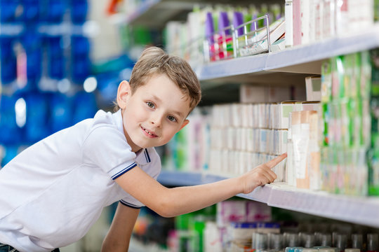 Little boy chooses cosmetics on the shelves of the store