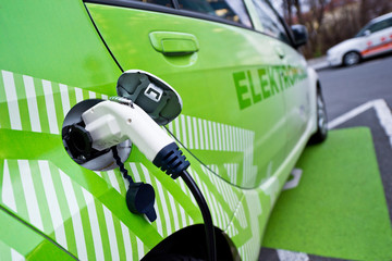 Detail of ecological green car re-fuelling, plugged in
