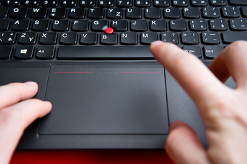 Blurred hands above the keyboard of red colored laptop