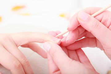 Beautician cleaning cuticles hands with cosmetic stick