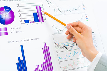 female hand pointing pencil on financial charts