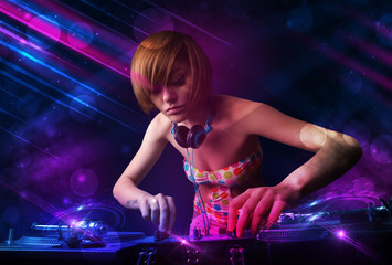 Young DJ playing on turntables with color light effects