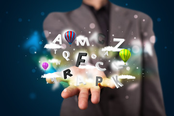 Young businessman presenting magical clouds with letters and bal