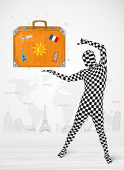 man in full body suit presenting vacation suitcase