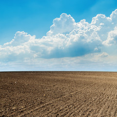 plowed field in spring and clouds over it