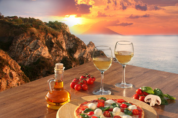 Italian pizza and glasses of wine against Calabria coast, Italy - obrazy, fototapety, plakaty