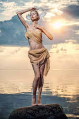 Fototapeta na wymiar Young beautiful woman as swan posing on the beach at sunset