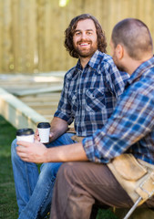 Fototapeta premium Happy Worker Holding Disposable Cup While Sitting With Coworker