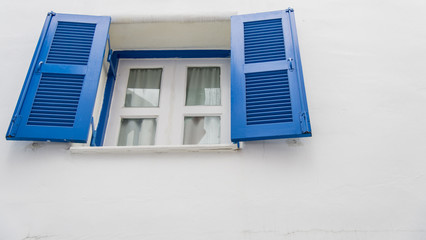 Open blue window on white wall