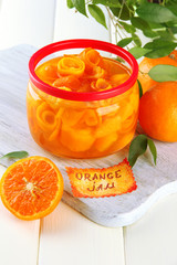 Orange jam with zest and tangerines, on white wooden table