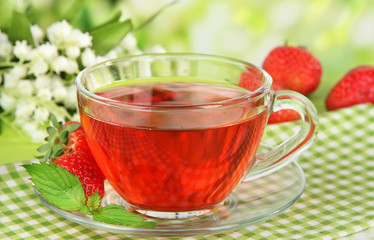 Delicious strawberry tea on table on bright background
