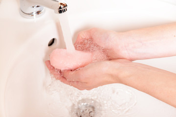 Fototapeta premium Close-up of human hands being washed under faucet in bathroom