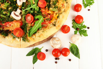 Tasty vegetarian pizza and vegetables on wooden table