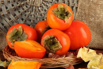 Ripe persimmons with nuts on table on wicker background