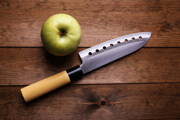 Kitchen knife and green apple,   on wooden background