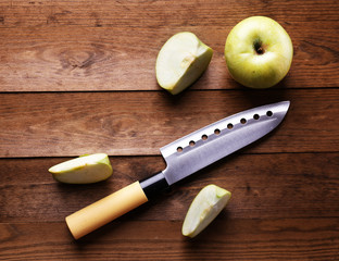 Kitchen knife and green apple,   on wooden background