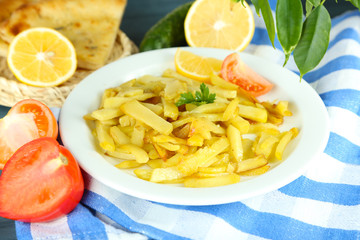 Ruddy fried potatoes on plate on tablecloth close-up