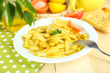 Fried potatoes on plate on wooden table close-up
