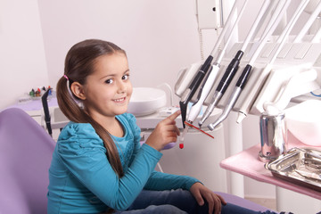 little girl in dental office with dentist tools