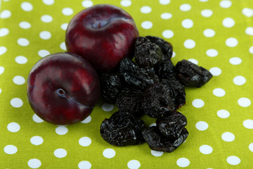 Fresh and dried plums, on color background