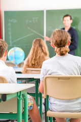Lehrer unterrichtet an Tafel Klasse in Schule