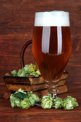 Glass of beer and hops, on wooden table