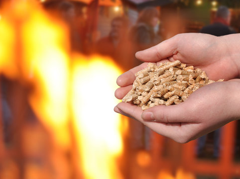 Hand mit brennenden Holzpellets, Feuer und Glut