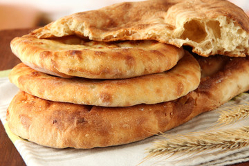 Pita breads with spikes on table on bright background