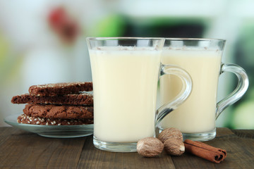 Cups of eggnog with cinnamon and cookies