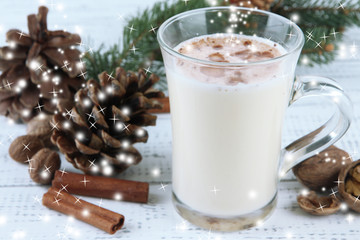 Cup of eggnog with fir branches on wooden background