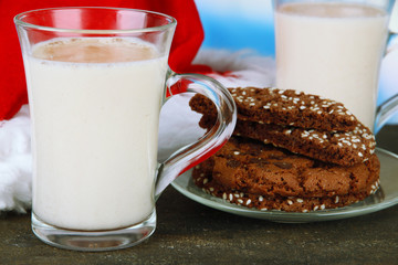 Cups of eggnog with cookies and Santa hat